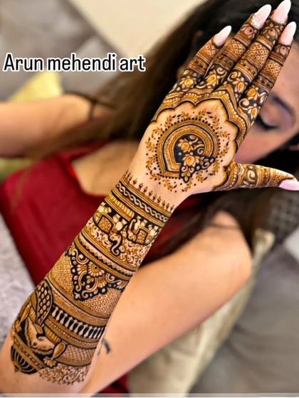 A stunning back-hand design featuring a central heart-shaped peacock motif, surrounded by delicate patterns that extend up the arm.