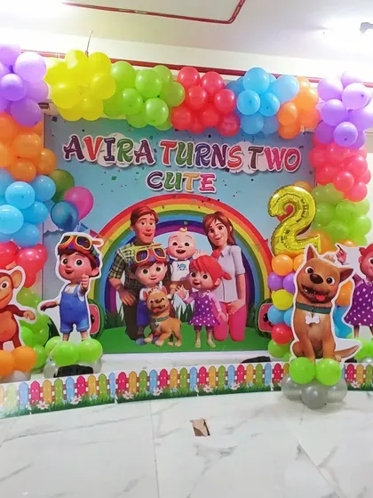 A full Cocomelon themed decoration for a second birthday party, perfect for toddlers. This setup includes a large, colorful backdrop with the entire Cocomelon family and friends, framed by a vibrant balloon garland. Life-sized character cutouts of JJ, TomTom, YoYo, and their animal friends bring the theme to life, making it an immersive experience for the little ones.