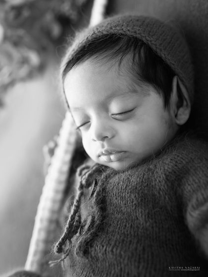 A black and white close-up of a newborn's face. The soft lighting and gentle expression create a beautiful and timeless portrait.