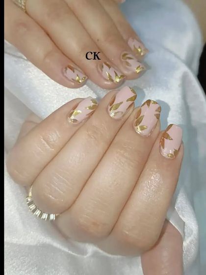 A chic design with a nude base and hand-painted gold leaf patterns.