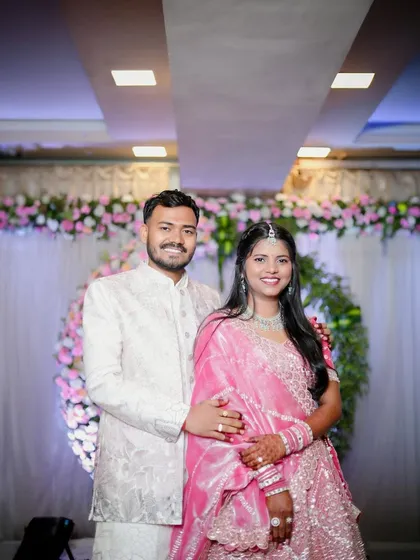 A smiling portrait of the couple at their engagement party. They stand together in front of the stage, looking happy and ready to celebrate with their family and friends.