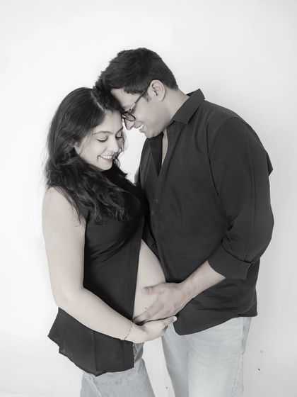 A classic black and white portrait capturing the intimacy and joy of pregnancy. The focus is entirely on the couple's happy expressions and connection.