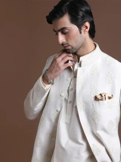 A detailed shot of the white open-style sherwani, highlighting the subtle texture and the precise, clean finish of the garment. The coordinated pocket square adds a final touch of polish.