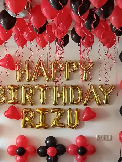 A simple yet impactful birthday room decoration. Red and black balloons on the ceiling, paired with "Happy Birthday" foil letters, create a classic and bold look.