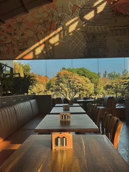 Sunlight streams into the Koteshwaram restaurant in Devanahalli. We combined a modern glass structure with traditional motifs and warm, natural materials to create a dining space that feels both elegant and deeply rooted in local culture.