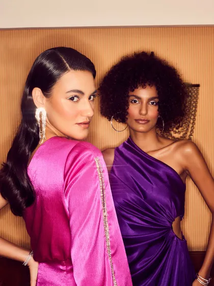 A close-up of the two models, highlighting the makeup and jewelry styling. The models' confident expressions and direct eye contact create an engaging and aspirational image.