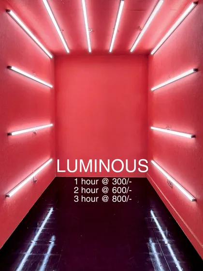 Welcome to the 'Luminous' booth. This room features vibrant pink walls and is framed by horizontal white tube lights on all sides, creating an immersive box of light. The rental prices are listed for this popular and eye-catching reel-making space.