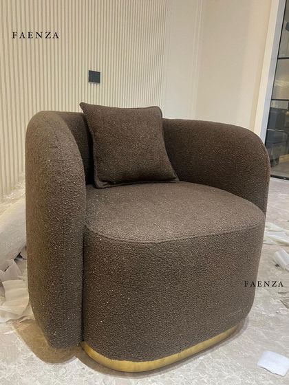 The Cloud Chair in a rich brown bouclé fabric. The chair's sculptural form and brass-finished swivel base make it a stylish and comfortable statement piece from every angle.