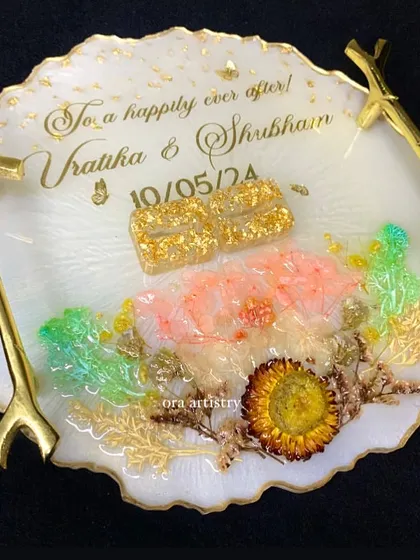 A close-up of an engagement ring platter, showing the custom ring holders and preserved flowers.
