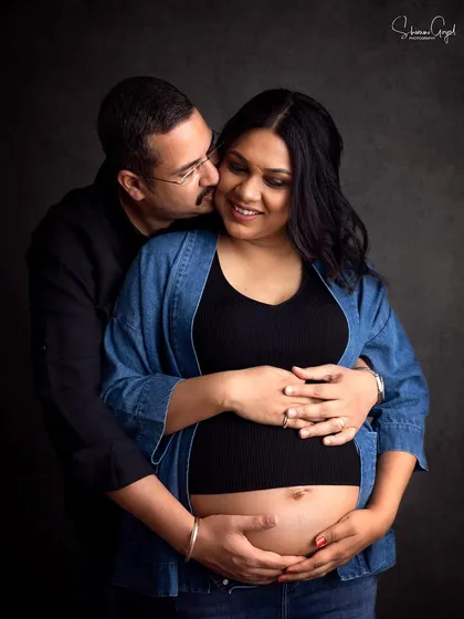 Candid moments are my favorite! This couple's joy is so real in this moody, dark-background portrait from their studio maternity shoot.