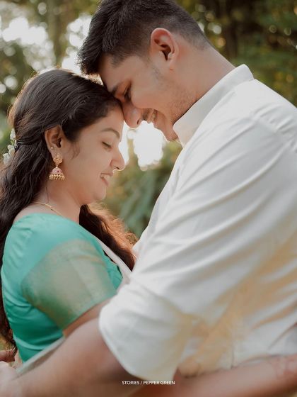 A close-up of Jayaram and Abirami, their foreheads touching in a moment of quiet connection. The soft backlighting adds a beautiful, gentle glow.