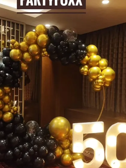 A classic black and gold theme for a 50th birthday, with a circular balloon arch and large light-up marquee numbers.