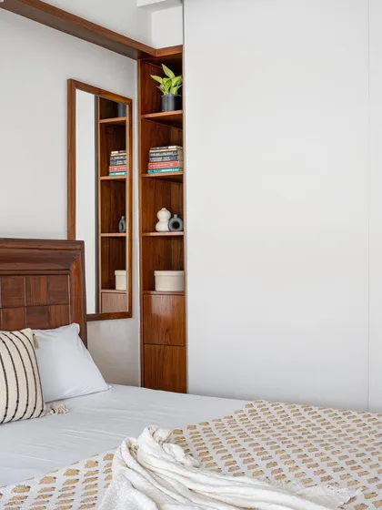 In the 'Gulmohar' primary room, we designed a full-length 9ft sliding wardrobe in a neutral palette. It provides a seamless backdrop, allowing the classical bed and study to stand out.