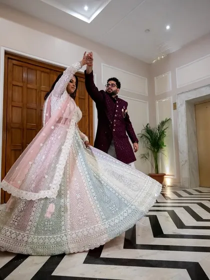A wide shot of the couple dancing, capturing the full sweep of the bride's lehenga and their graceful movement.
