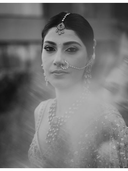 A classic black and white bridal portrait. The soft focus and the bride's direct gaze create a timeless and soulful image, capturing her beauty and poise before the ceremony.
