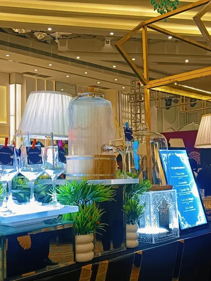 A detailed shot of a beautifully styled bar corner. It features elegant glassware, drink dispensers, a lit menu, and decorative plants, showcasing my attention to detail.