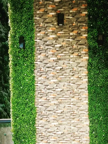This balcony wall combines the textures of natural stone cladding with strips of artificial boxwood. The addition of modern up-and-down lights highlights the different materials.
