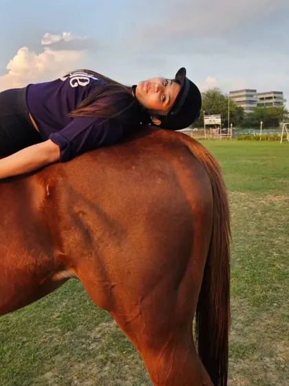A rider relaxes completely on her horse's back, showing the immense trust and comfort between them.