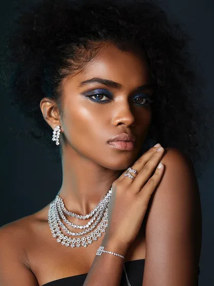 A stunning blue electric eye makeup look on a deep skin tone, paired with sparkling diamond jewelry. Our artists learn to create luxury and glamour.