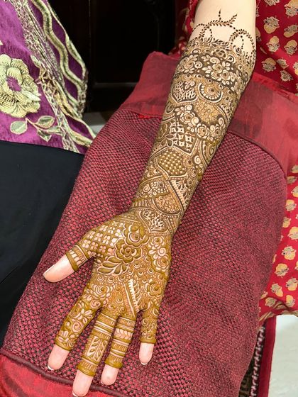 A full-arm view of a beautiful Indian bridal design. The patterns are intricate and the coverage is flawless, with a delicate crown detail at the top.