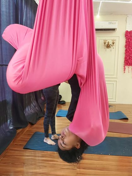 A student hangs in a gentle inversion during an aerial pilates class. This move is great for decompressing the spine and building core control.