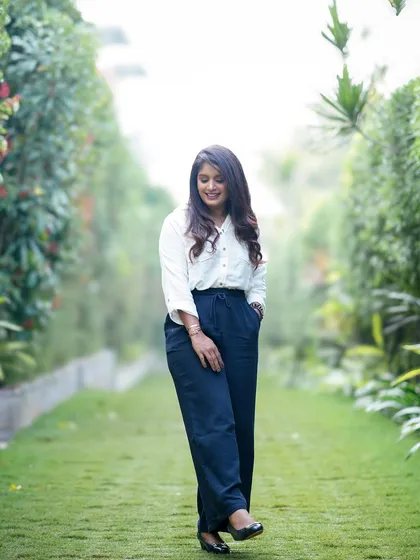 A candid shot of a woman walking and smiling in a beautiful garden setting during her individual portrait session.