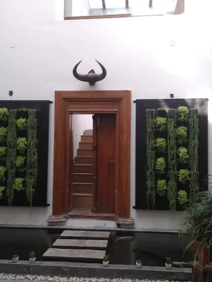 In this unique villa courtyard, we installed two symmetrical vertical gardens to frame a doorway, creating a grand and natural entrance. The design works with the indoor water feature and stone path for a cohesive, tranquil feel.