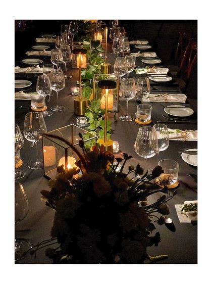 A dark, moody tablescape with elegant glassware and modern table lamps, perfect for a contemporary fine-dining event.