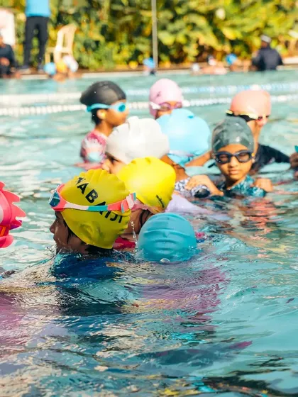 We believe swimming is about more than just technique; it's about building confidence and making friends. Here, a group of our young swimmers listens intently during a lesson, showcasing the fun, social, and engaging atmosphere we cultivate in our kids' batches.