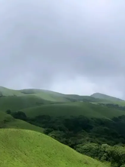 The rolling green hills of the Western Ghats, partially covered in monsoon clouds.
