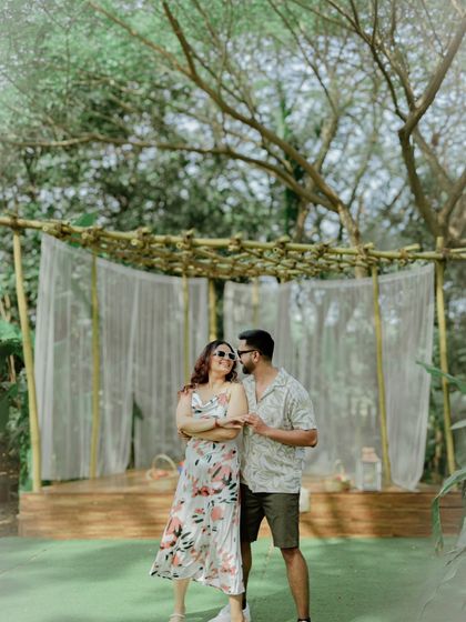 A full shot of the couple in their casual outfits, standing in front of a rustic, bohemian-style backdrop. This shows the complete setup for a themed, playful shoot.