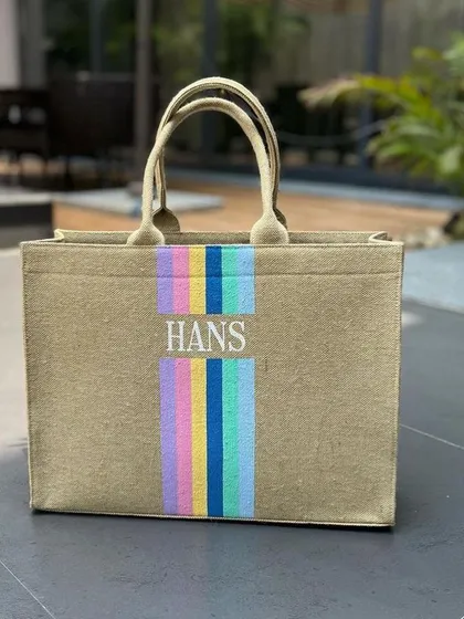 Our jute canvas tote bag with a fun pastel rainbow stripe. We can embroider a name or initials, as shown here with 'Hans'.