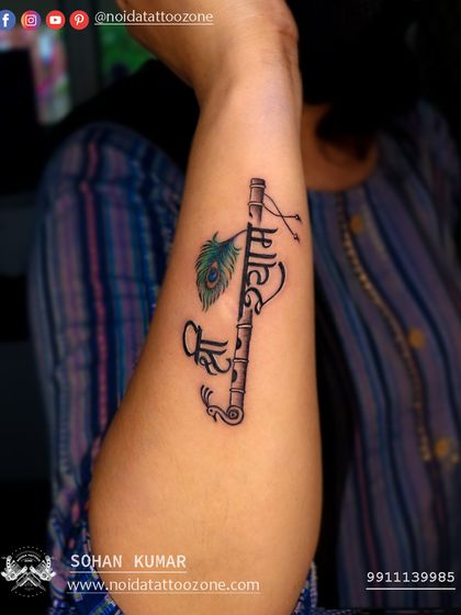 A custom script tattoo of "Shree Shyam" integrated with a flute and a small peacock feather. This design is a great example of how we blend names and symbols for a personal and devotional piece.