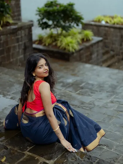 An over-the-shoulder pose that is both classic and engaging. The model is seated on stone steps, looking back with a gentle smile, creating a dynamic and flattering portrait.