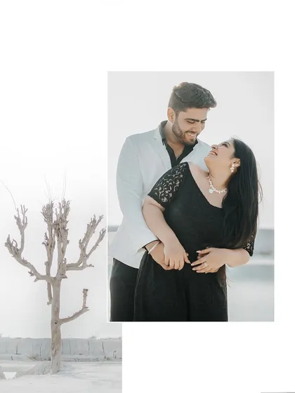 An artistically composed shot with a lone tree, framing a happy and intimate moment between the couple.