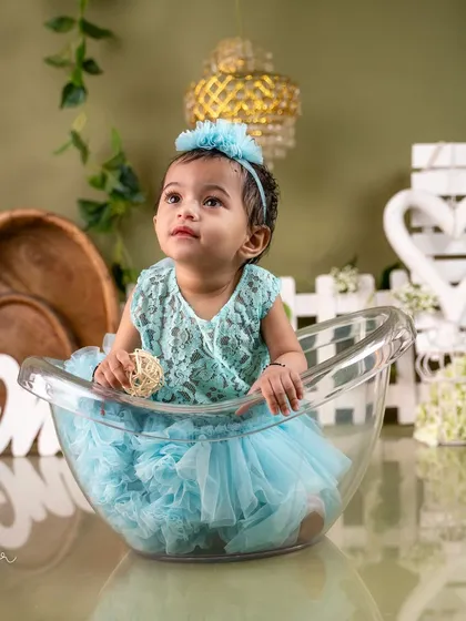 A sweet portrait in a miniature tub, part of a beautifully styled first birthday session with a rustic green and teal theme.