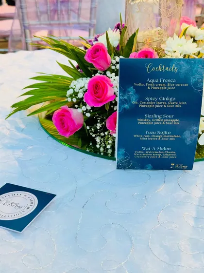 A custom cocktail menu and matching coaster for Neville and Fariha's celebration, placed beautifully next to a floral centerpiece.