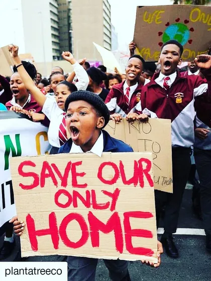 This is the heart of our mission. A young activist at a climate march holds a sign that reads "Save Our Only Home," capturing the passion and urgency of the global movement we are proud to be a part of.
