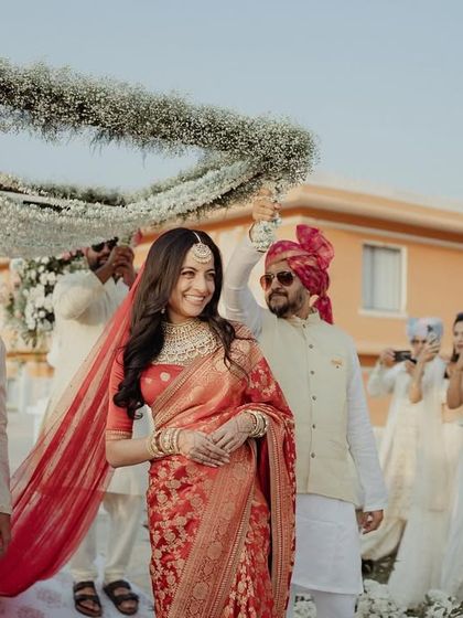 The smiling bride making her way to the mandap, surrounded by her loved ones.