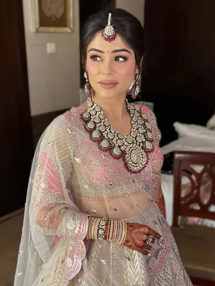 A three-quarter view of a bride with a soft updo, her dupatta draped gracefully over her head. The hairstyle is secure enough to hold the veil in place all day.