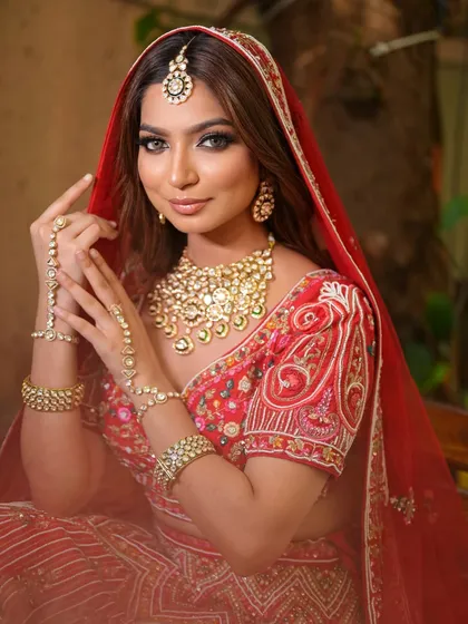 A full view of a bride in a traditional red lehenga, adorned with a complete Polki jewellery set. The hathphool and maang tikka tie the entire royal look together.