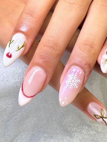 A close-up of the winter-themed nail art, showing the detail in the hand-painted reindeer, snowflake, and gold bow.