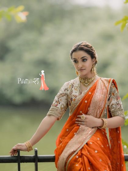 The full view of our stunning orange Navwari saree, captured in a serene outdoor setting. This image shows the beautiful fall of the fabric and the traditional yet fresh appeal of the entire ensemble.