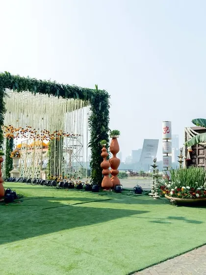 A wider view of the grand floral entrance, showing how the green archway and traditional elements create a stunning visual path against the open sky, perfect for a large-scale outdoor wedding.