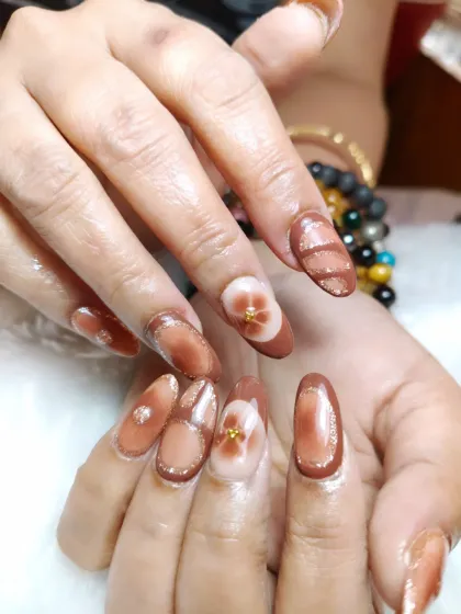 A full view of the brown cat-eye nail set with intricate floral and geometric hand-painted designs.