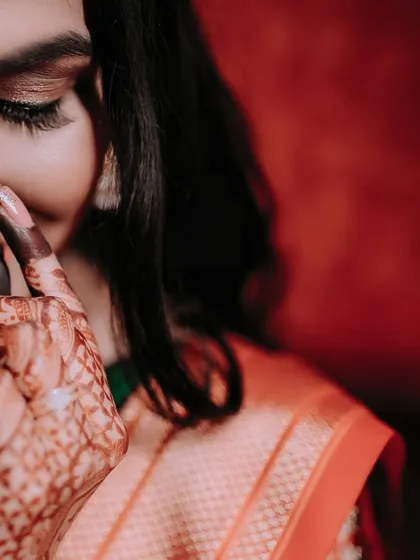 A detailed close-up shot focusing on the bride's intricate mehendi and her traditional nath (nose ring). This type of photo highlights the small but important details of the bridal look.