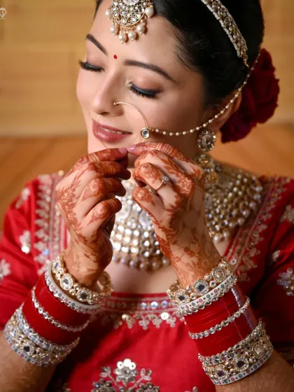 A close-up of a Himachali bride adjusting her traditional nose ring (nath), a classic and graceful getting-ready shot.
