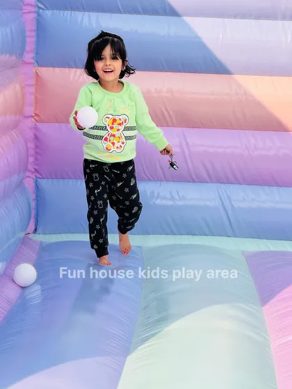 A happy girl holds a ball inside our pastel bounce house. The colorful, striped interior makes for a cheerful and engaging play environment.