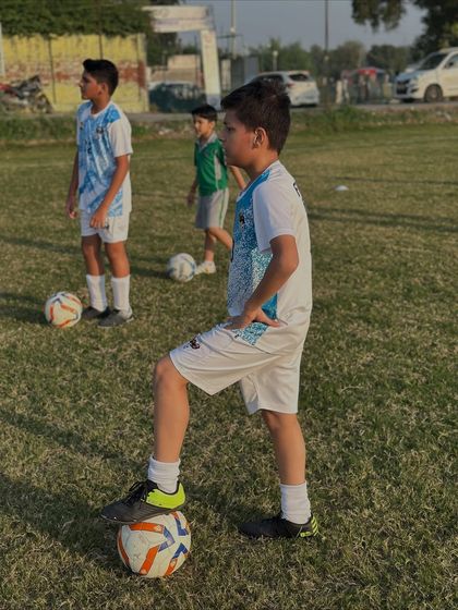 A young player with his foot on the ball, demonstrating confidence and control. This pose is a classic sign of a player ready for action.