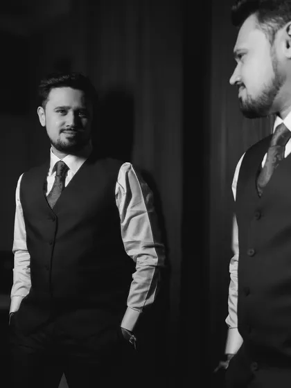 A black and white portrait of the groom looking at his reflection.